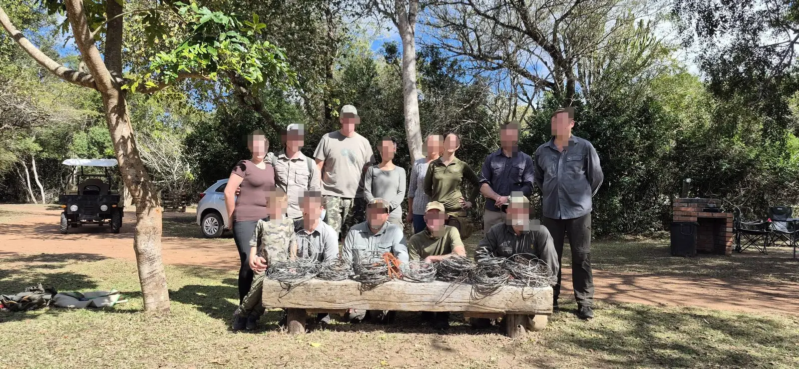 Snare Aware volunteers, faces blurred, gathered behind a bench piled with the coils of snare wire they removed